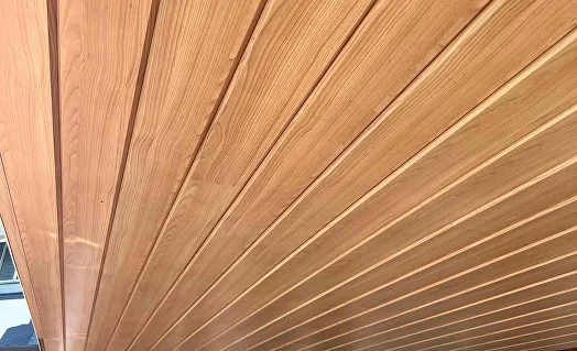 Woodgrain aluminium lining boards across an alfresco ceiling beside the water