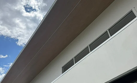 White house facade with a horizontal woodgrain aluminium slat band