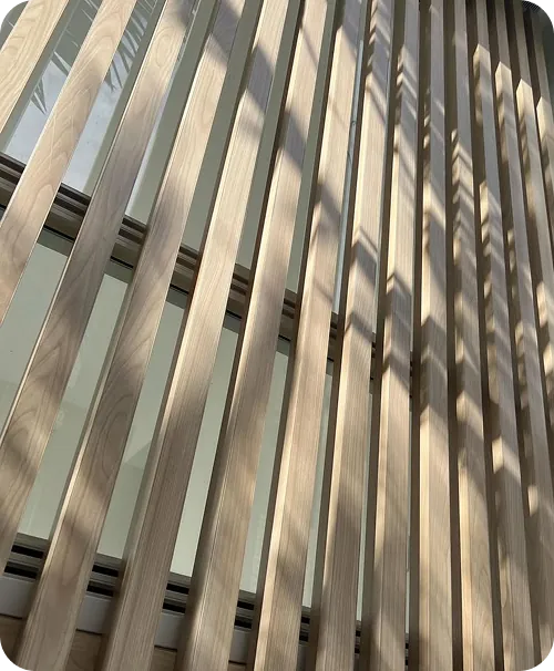Diagonal shadows falling across a pale woodgrain aluminium batten screen