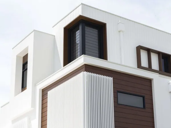 White-clad home with dark woodgrain aluminium panels and vertical fin screens