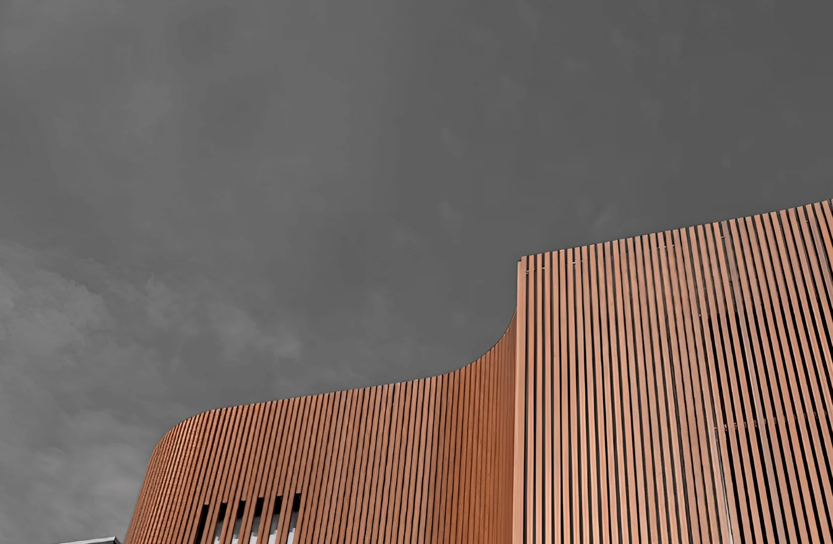 Curved commercial facade corner clad in solid woodgrain aluminium fins