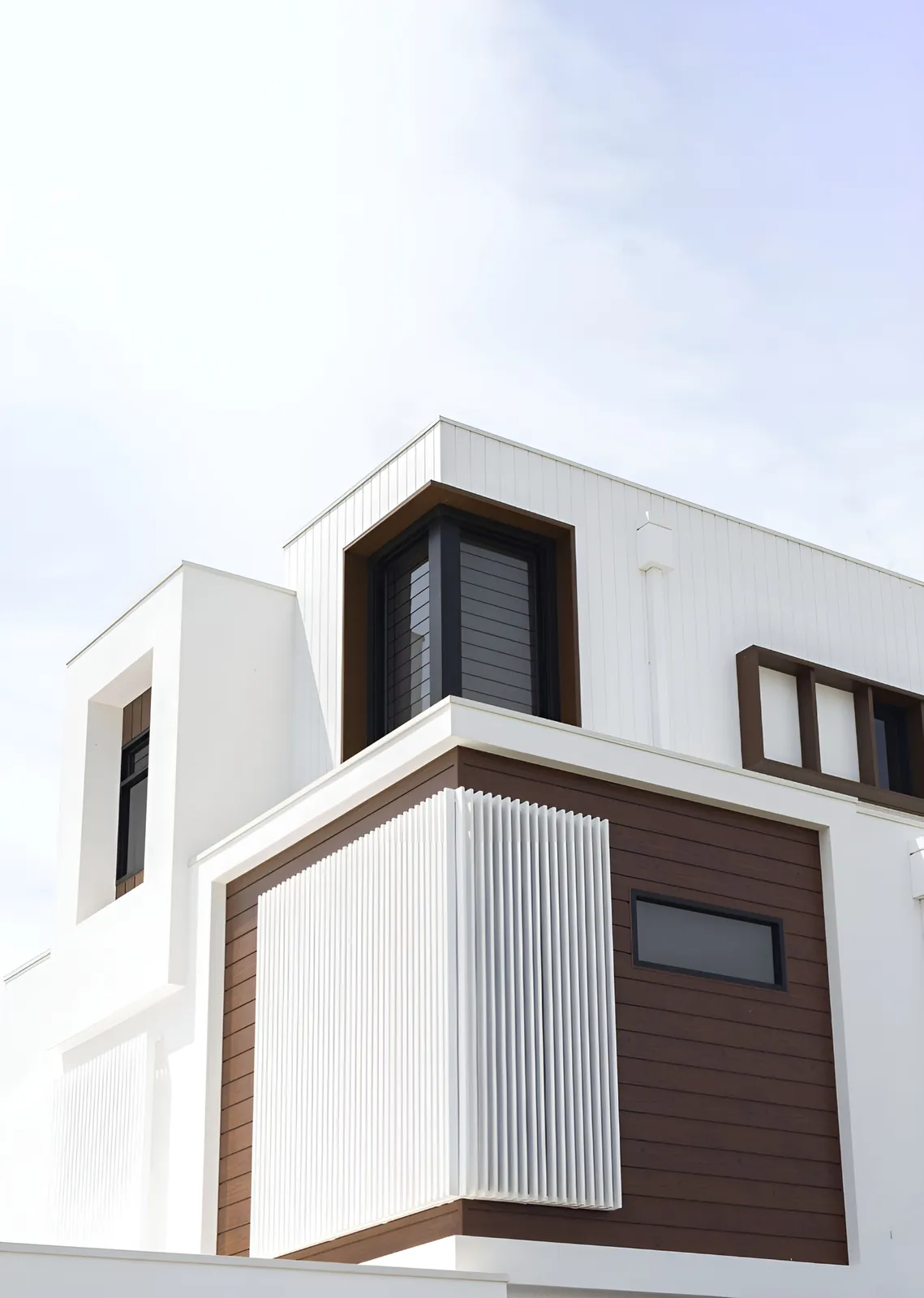 White home contrasting dark woodgrain aluminium panels with white vertical fins